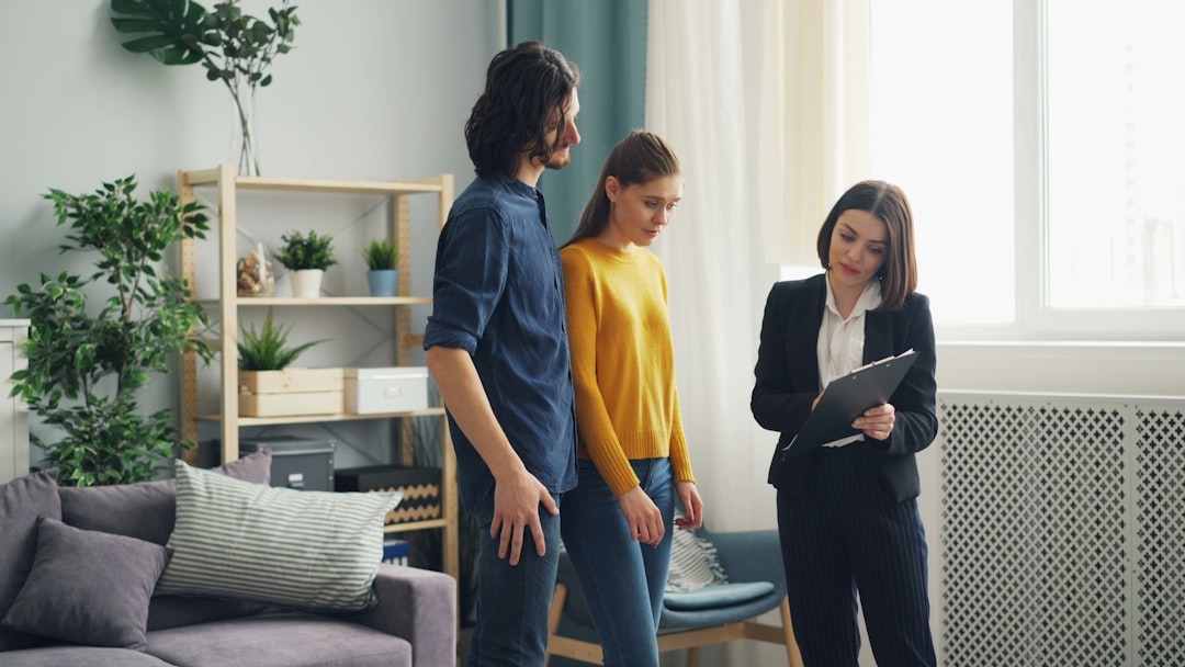 Real estate agent shows a modern living room to a couple.